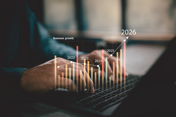 Business growth chart overlaying hands typing on laptop keyboard with future data trend to 2026