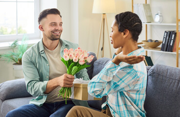 A happy diverse interracial couple in love celebrating their relationship anniversary. At home on a...