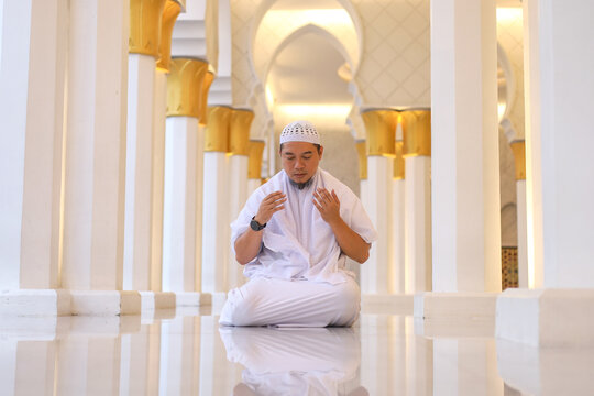 Front View Of Asian Muslim Man Raising Hands In Dua Prayer With Reflection