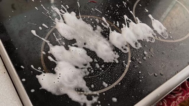 Spraying Cleaner on Glass Ceramic Cooktop Creating White Foam