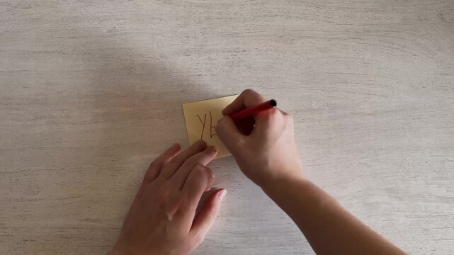 Hands Writing YES on Sticky Note with Red Marker Approval Concept