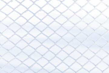 Fototapeta premium Textured snow-covered fence, metal fence