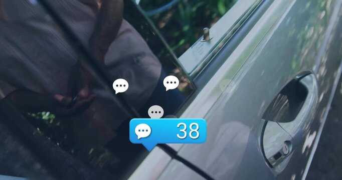 Mature male crouching beside silver car, plugging EV charger for tech demo, showing chat bubbles