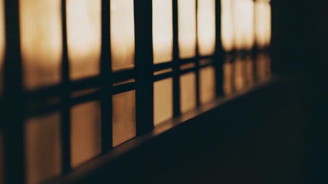 Sunlight entering through a window creating a repeating pattern of dark grid shadows and bright rectangular light shapes on a warm indoor wall, symbolizing reflection and contemplation
