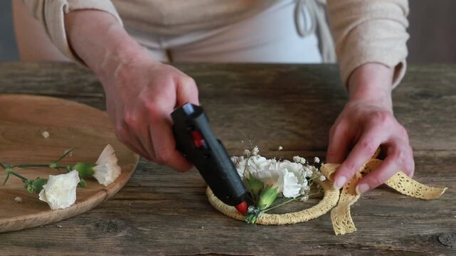 Florist at work: woman shows how to make small wreath with carnation flowers and gypsophila paniculata twigs. Step by step, tutorial. Images available.
