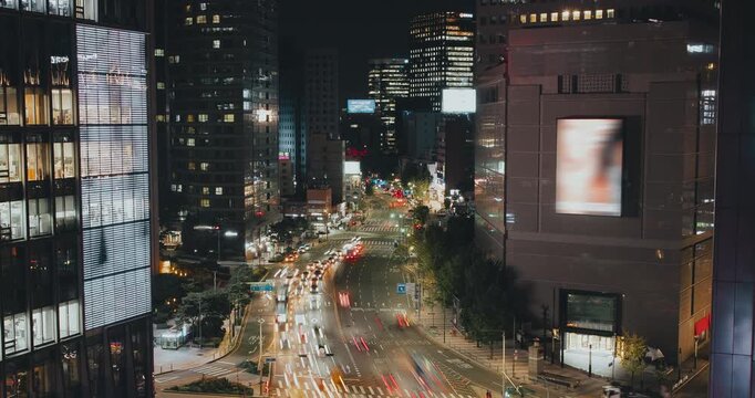 A vibrant urban night scene captures the continuous flow of traffic along a bustling city street with bright lights and towering buildings. Time-lapse, Seoul, South Korea
