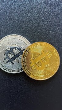 Top view of Rotating Bitcoin coins on dark textured surface. Vertical video