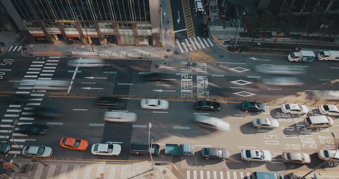 A vibrant urban street captures the continuous flow of vehicles moving through intersections, emphasizing the rhythm of city traffic. Time-lapse, Seoul, South Korea
