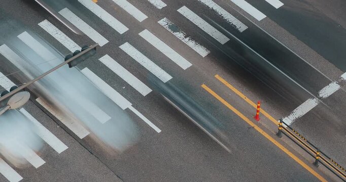 Vehicles move through a bustling urban crosswalk, highlighting the dynamic flow of traffic and the interaction of cars with road markings. Time-lapse, Seoul, South Korea
