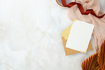 Minimalist invitation scene with an envelope and card on a marble background with copy space.