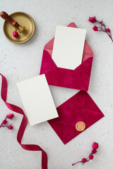 Vertical flat lay of romantic wedding stationery with magenta envelopes and blank cards.