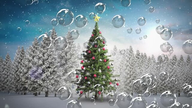 Animation of bubbles floating and snow falling over decorative christmas tree on winter landscape