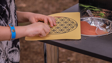 Child creating colorful sand art at market