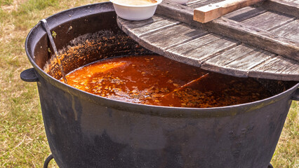 Hearty stew cooking in large iron cauldron