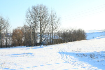 Obraz premium A snowy field with trees and a building in the background