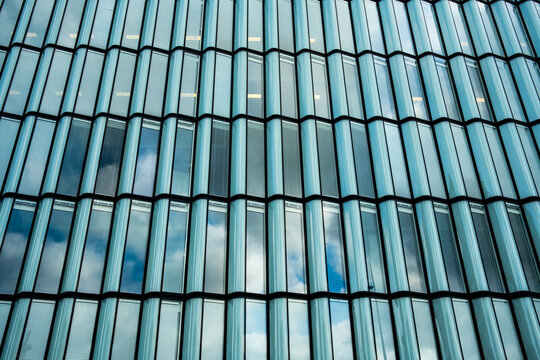 Modern teal glass facade with windows grid pattern and abstract texture offering clean architecture background for branding design and corporate use
