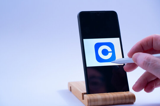 Hand interacting with a smartphone screen showing the coinbase cryptocurrency exchange logo