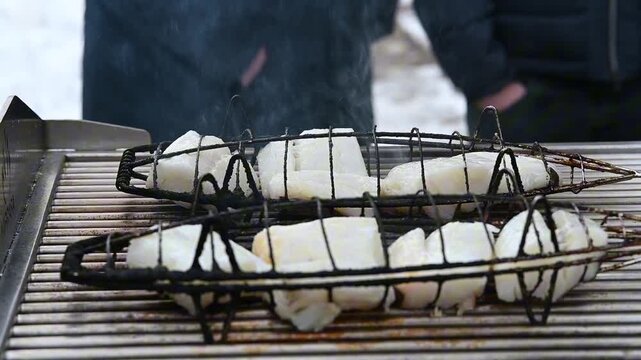 A close-up of grilled codfish cooked over a charcoal barbecue, showcasing traditional Mediterranean and Portuguese cuisine.