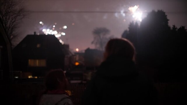 Silhouette of mother and child watching fireworks in night sky during New Year celebrations in Oosterbeek.
