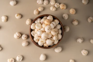 Fototapete Zu Essen Phool Makhana, Fox Nut, Lotus Pops Seeds, Gorgon nut, Euryale Ferox on a wooden bowl with beige background.  © sdx15