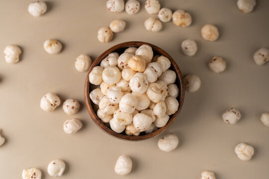 Phool Makhana, Fox Nut, Lotus Pops Seeds, Gorgon nut, Euryale Ferox on a wooden bowl with beige background.