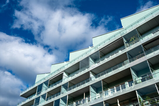 Modern architecture apartment residential building facade with glass urban balcony and clouds seen from low angle perspective upward exterior