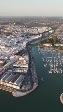 Scenic vertical aerial shot rising above Ayamonte harbor, expanding the view to include the riverside landscape and horizon.