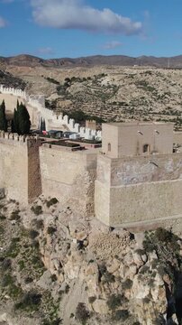 Vertical aerial orbit showcasing the Baluarte del Saliente tower in Almer&iacute;a Alcazaba, highlighting its medieval architecture and strategic position.