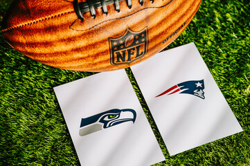 Obraz premium American football with Super Bowl LX logos for Seattle Seahawks and New England Patriots on green grass, Lombardi Trophy next to it, at Levi’s Stadium in Santa Clara