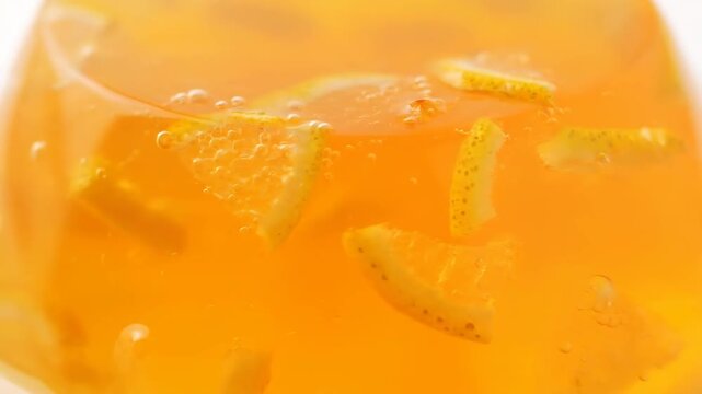 Macro View of Vibrant Orange Gelatin Dessert with Embedded Citrus Fruit Slices and Refreshing Bubbles, Perfect for Summer Treat Concepts
