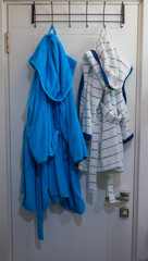 Terry bathrobes hang on hooks in the bathroom