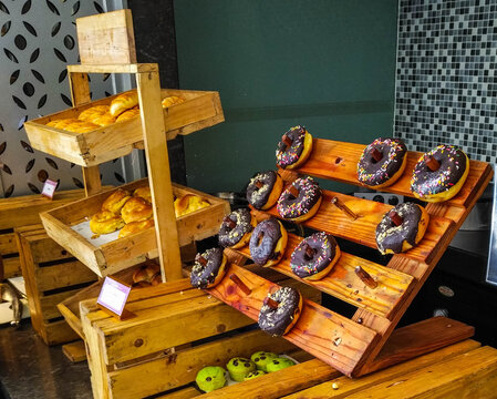 Hotel breakfast buffet with donuts, pastries, and dessert toppings arranged on rustic wooden stands. Perfect for hospitality, travel, restaurant, catering, and food service design projects.