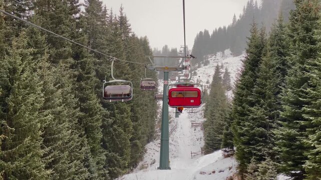 A wide-angle shot of skiers on a chairlift at Alpe di Siusi in the Dolomites. A panoramic shot of the lift ascending the snow-covered slopes of the Seiser Alm. Winter sports in the Italian Alps skiers