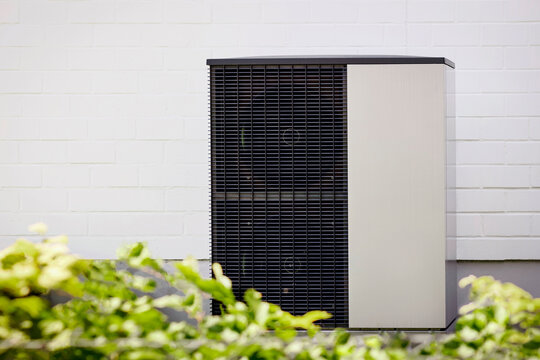 Heat Pump Air to water for House. Modern Air-source heat pump Transferring Thermal Energy. Smart Energy Saving Electric Residential Heating System on Building Wall Background. 