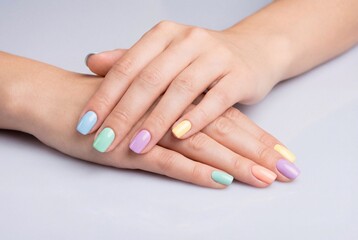 Naklejka premium Woman hands with colorful pastel manicured nails on light surface