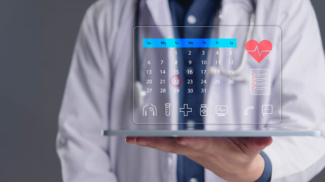 Doctor holding digital tablet with calendar interface for medical appointment booking. Healthcare technology concept for scheduling heart checkup, cardiology consultation, and telemedicine service.