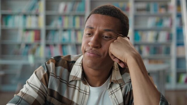 Bored unhappy African American man male student in library tired guy looking away in boredom study burnout pensive mood learning frustration fatigue university college thinking idea negative mindset