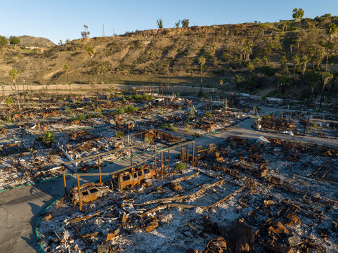 Aerial view of scorched remains of homes and structures, a desolate landscape contrasting with the hillside in the background, Pacific Palisades, California, United States.