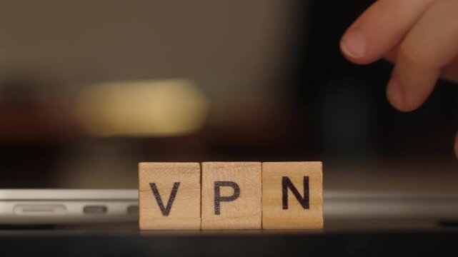 Child hand arranging wooden letters &ldquo;VPN&rdquo; near a laptop, cybersecurity and privacy concept