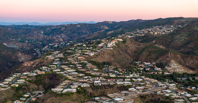 Aerial view of houses nestled in the rolling hills under a soft, pastel sky, Los Angeles, California, United States.