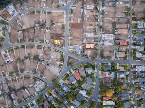 Aerial view of a patchwork of residential lots, some barren and awaiting construction, others blooming with life, divided by winding streets, Los Angeles, California, United States.