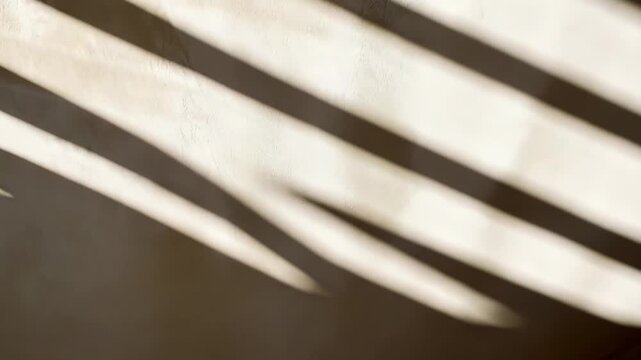 Sunlight creating a striking abstract pattern of parallel diagonal shadows and bright lines on a beige textured wall, conveying a sense of calm, natural illumination, and architectural beauty