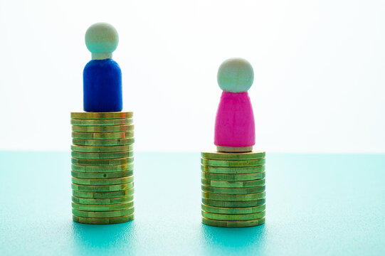 Concept of unequal pay in the workplace between men and women. Gender Pay gap: wooden figures and piles of coins.