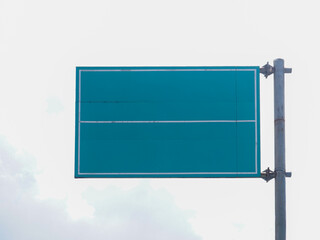 ​Empty green highway road sign on metal pole against cloudy sky. Blank street board with copy space for text, direction, or advertising mockup