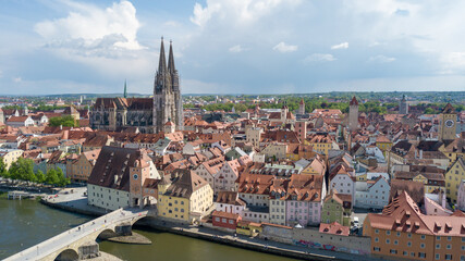 Obraz premium Regensburg, Germany - May 19, 2021: Drone flight over stone bridge over the Danube with cathedral