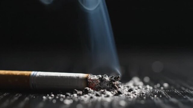 Close-up of a smoldering cigarette with ash and smoke against a dark background, symbolizing addiction and unhealthy habits