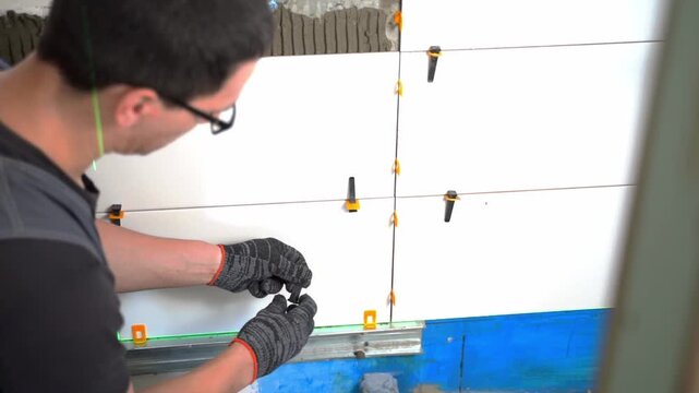 A builder lays tiles on a wall in a residential building