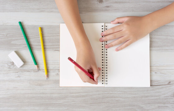 A child writing letters or illustrations in a notebook. ノートに文字またはイラストを書く子供