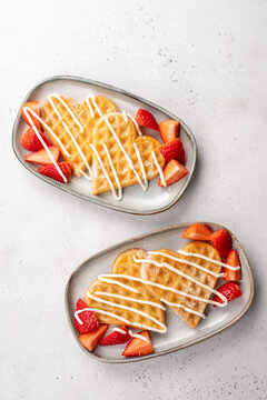 Heart-shaped waffles with strawberries served on plates during breakfast or brunch time