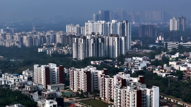 Drone footage of urban housing clusters, showing compact apartment blocks, green pockets, and a hazy skyline highlighting growing density and air quality challenges.